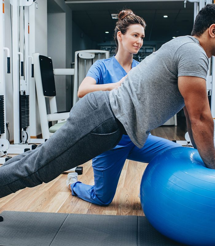 physiotherapist helps a man doing exercises for the rehabilitation and restoration of the body.